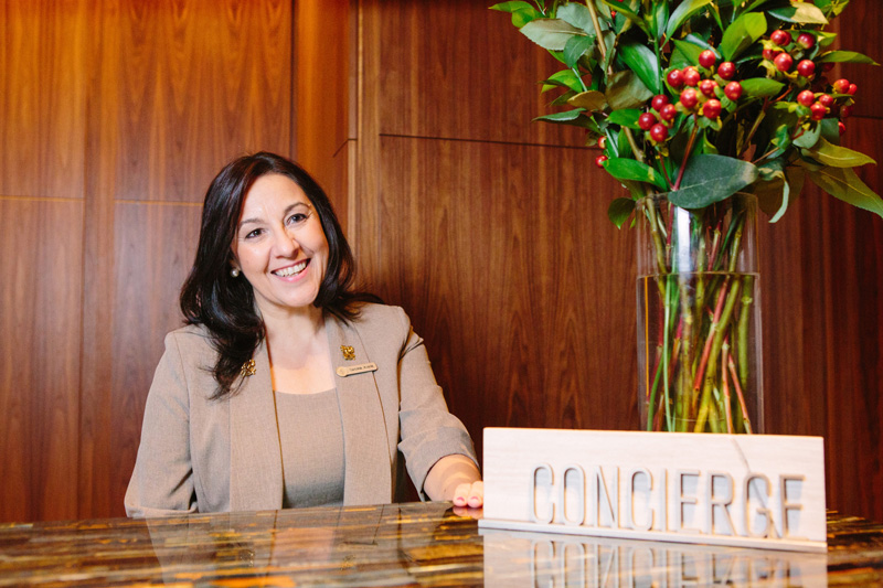 Carolina Avaria Four Seasons Hotel Toronto Sitting At Desk With Concierge Sign