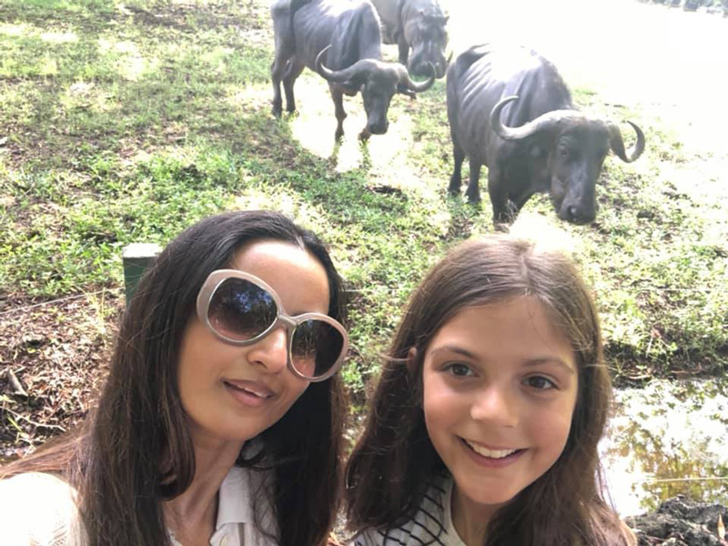 Farzana Baduel And Daughter Smiling On Vacation in Kenya With Water Buffalos In The Background