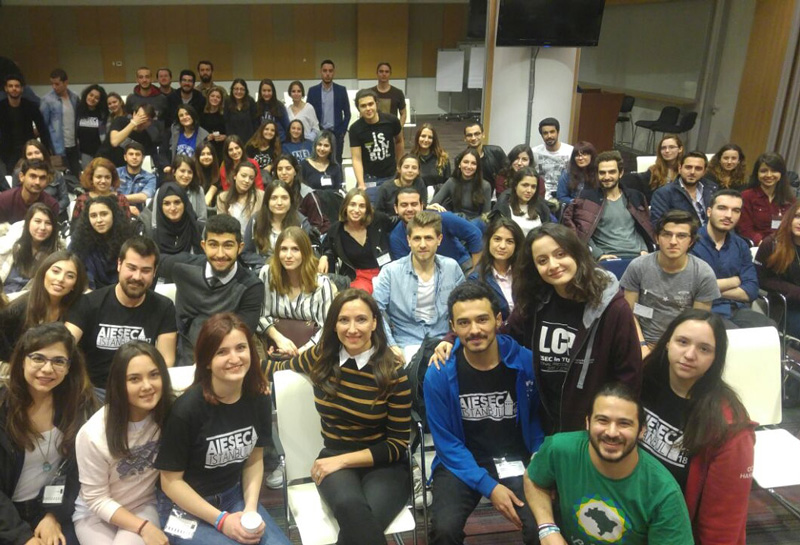 Irem Tuzunalper Sitting And Surrounded With Large Crowd Of Students