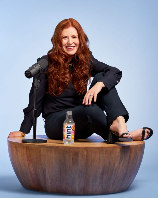 Kara Goldin Smiling And Sitting By Microphone And Bottle Of Hint Water 