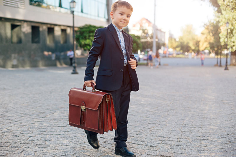Young Boy In Business Suit Holding Briefcase Walking Confidently On Street