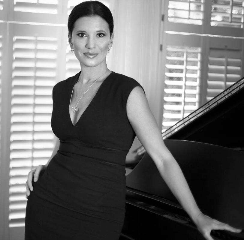 Black And White Photo Of Olga Balakleets In Black Dress Leaning On Piano