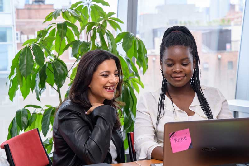 Reshma Saujani Sitting With Black Student Of Girls Who Code Looking And Smiling At Computer Screen