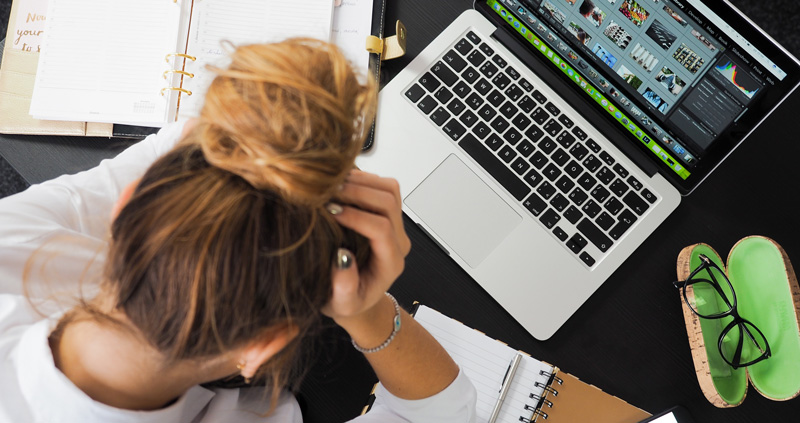 Woman With Hands In Hair Looking Sad Sitting And Hunched Over Computer