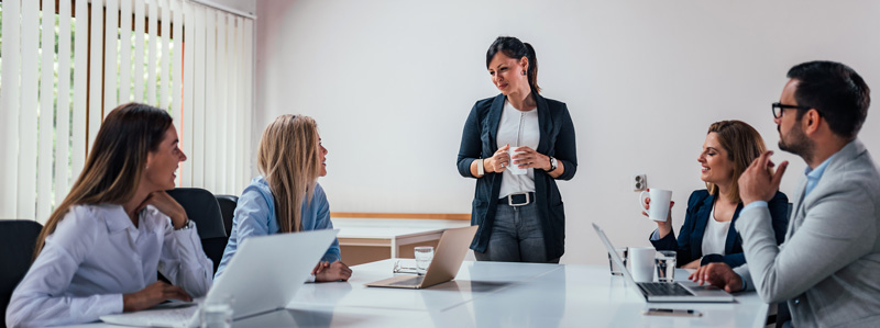 Woman Leading Business Meeting With Men And Women In Conference Room